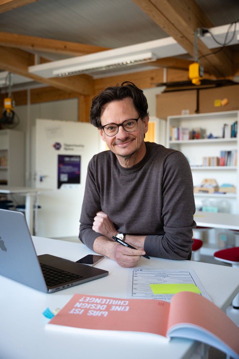 Ein mann schaut an den Tisch gelehnt in die Kamera