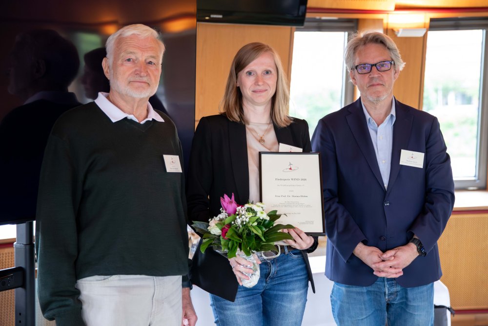 Eine Frau steht mit Blumenstrauß zwischen zwei Männern