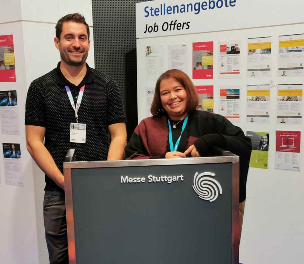Benjamin Fazio und Dragana Sobot auf dem careerHUB (im Hintergrund Stellwände mit über 100 Stellenanageboten für Technische Redakteure und Übersetzer)