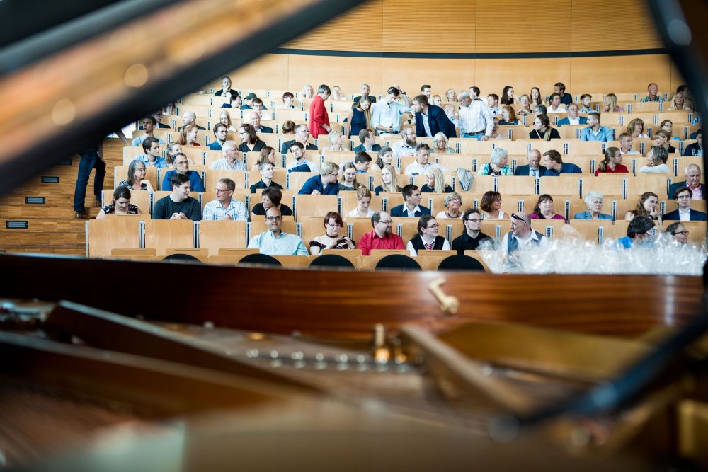 Blick ins Publikum durch den Deckel des aufgeklappten Klaviers.
