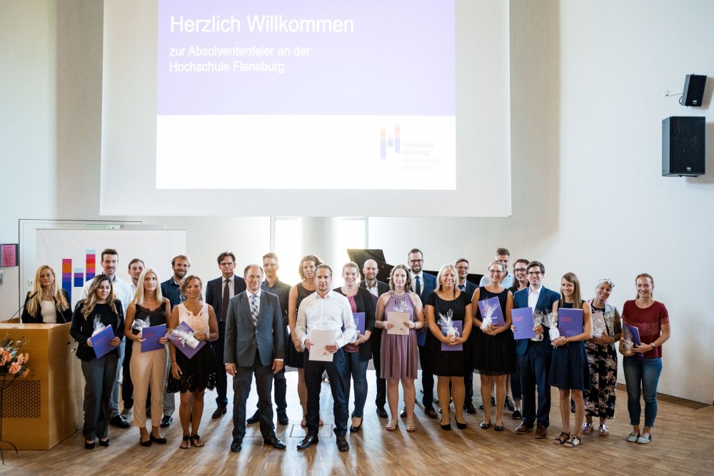 Gruppenbild von einem Teil der Absolventinnen und Absolventen mit Dekan des fachbereichs Wirtschaft, Präsident und der Leiterin des Studierendenservice.