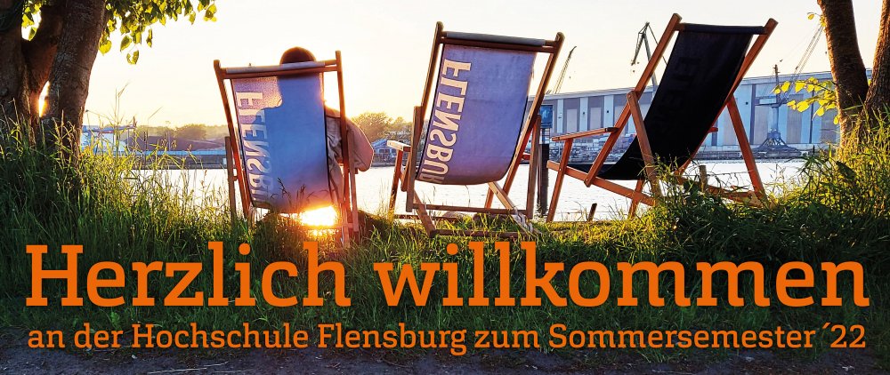 Drei Liegestühle, auf denen "Flensburger" steht, sie blicken auf sonnenbeschienenes Wasser.