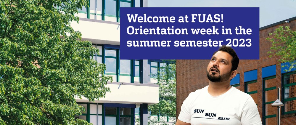 Male person looking curiously at a dark blue box with white writing in it. The background ogf the image is a picture of one of FUAS' buildings.