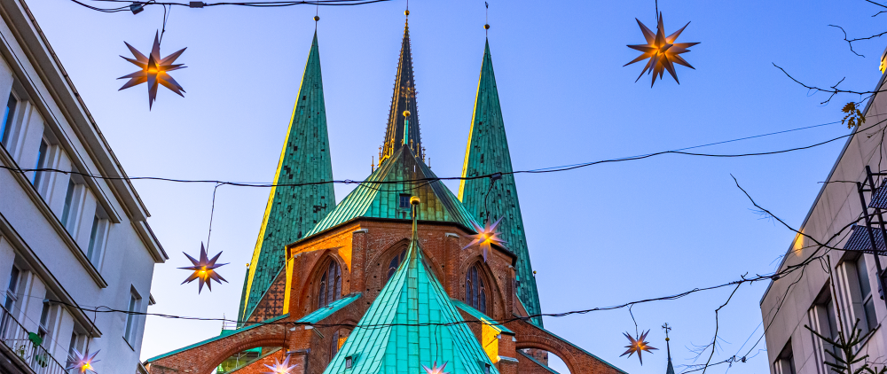 Foto der Marienkirche in Lübeck mit blauem Himmel und weihnachtlicher Beleuchtung.