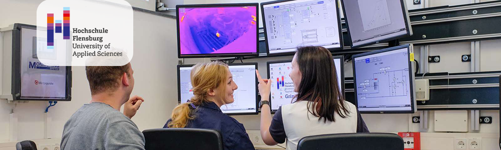 Zwei junge Frauen und ein junger Mann sitzen an einem Schreibtisch mit sechs Monitoren.