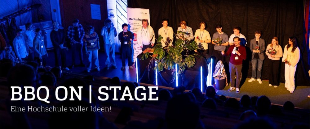 In einem dunklen Hörsaal steht eine große Gruppe von Studierenden vorne im Scheinwerferlicht. Dazu Text: BBQ On Stage. Eine Hochschule voller Ideen!