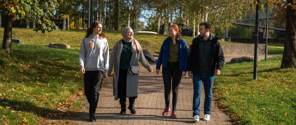 Eine Gruppe mit Menschen auf dem grünen Campus.