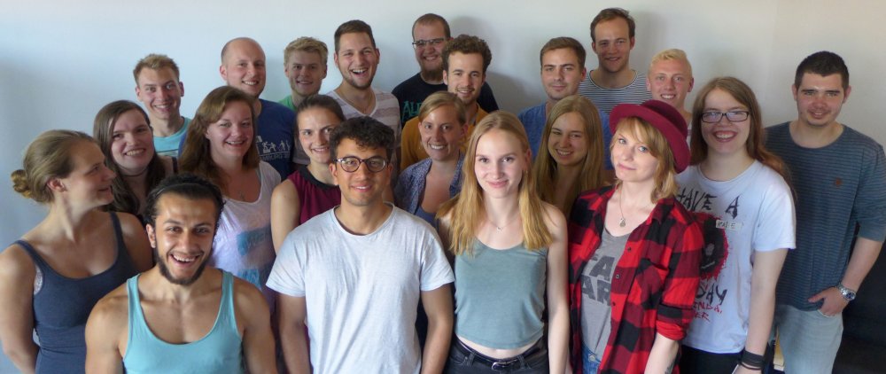 Mentorinnen und Mentoren des Jahrgangs 2018/19: Eine Gruppe von ca. 20 Studierenden posiert lachend vor einer weißen Wand.