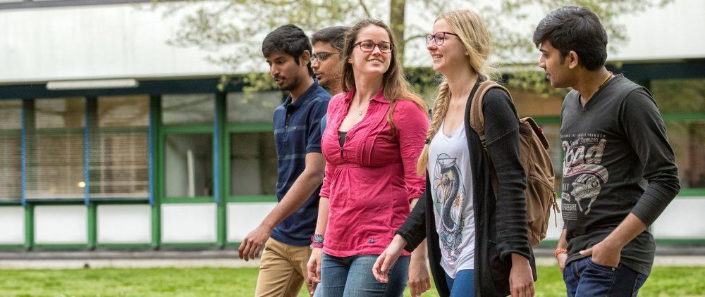 Eine Gruppe Studierender läuft im Gespräch über den Campus.