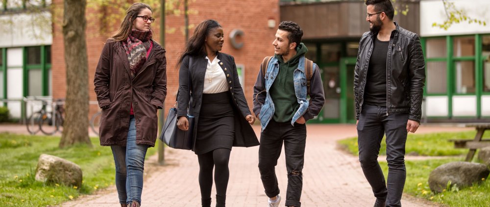 Gruppe Studierender läuft über den Campus.