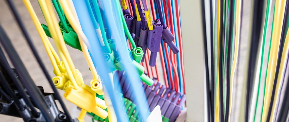 Zahlreiche verschieden farbige Kabel, die nebeneinander her verlaufen oder hängen.