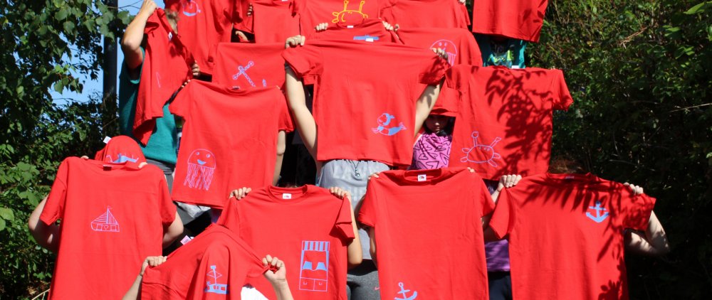 Rote T-Shirts, die von Menschen, die man nicht erkennt, hochgehalten werden.