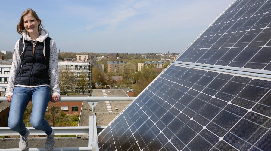 Studentin neben den Solarzellen auf dem Hochschulgebäude