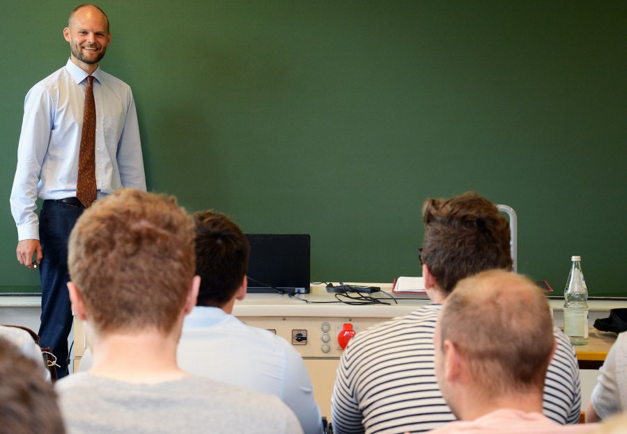 Dirk Volta vor einer Gruppe Studierender, er steht mit dem Rücken zu einer Tafel.