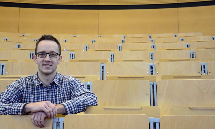 Student Dominik in den leeren Reihen eines Hörsaals.