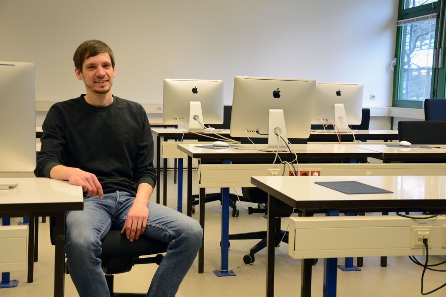 Jan Christiansen sitzt in einem der Computerlabore der Hochschule Flensburg.
