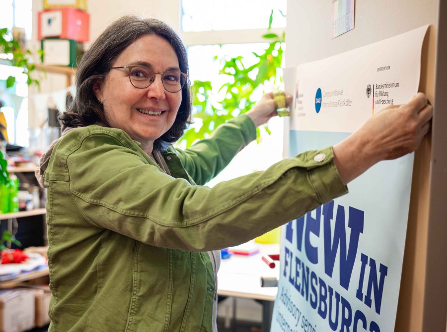 Eine Frau klebt ein Poster an die Tür