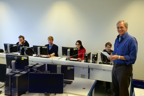 Martin von Schilling im Seminarraum, im Hintergrund arbeiten Studierende an Computern.
