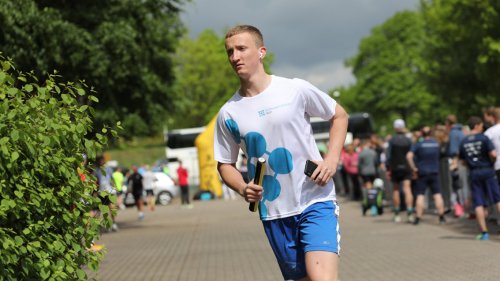 Ein junger Mann joggt am Fotografen vorbei, er trägt einen Staffelstab und ein Trikot der Schleswig-Holstein Netz GmbH.