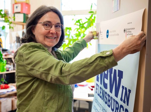 Eine Frau klebt ein Poster an die Tür