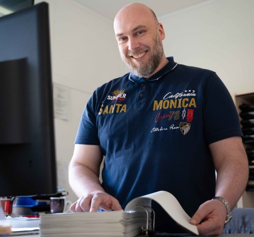 Ein Mann steht an einem Tisch und hat ein Buch vor sich