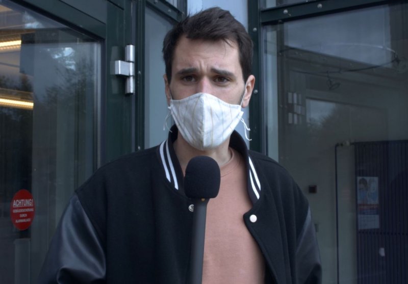 Student mit Maske, der in ein Mikrofon spricht.