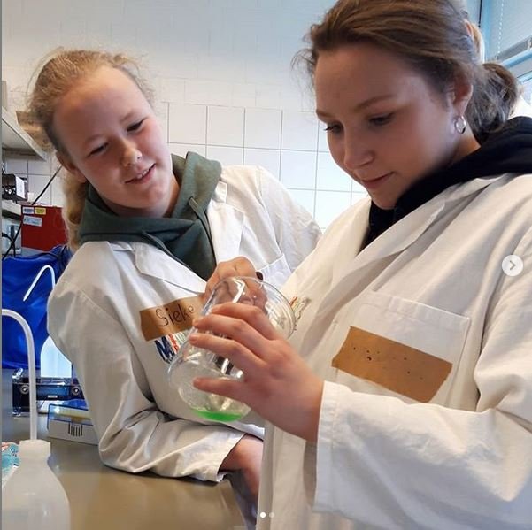 Zwei Mädchen in Laborkitteln pipettieren.