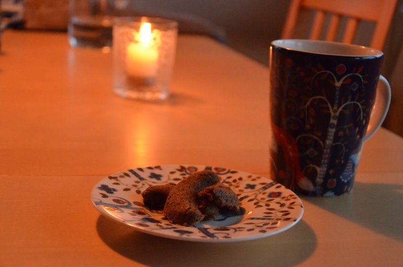 Teller mit Gebäck, Tasse und Kerze auf einem Tisch.