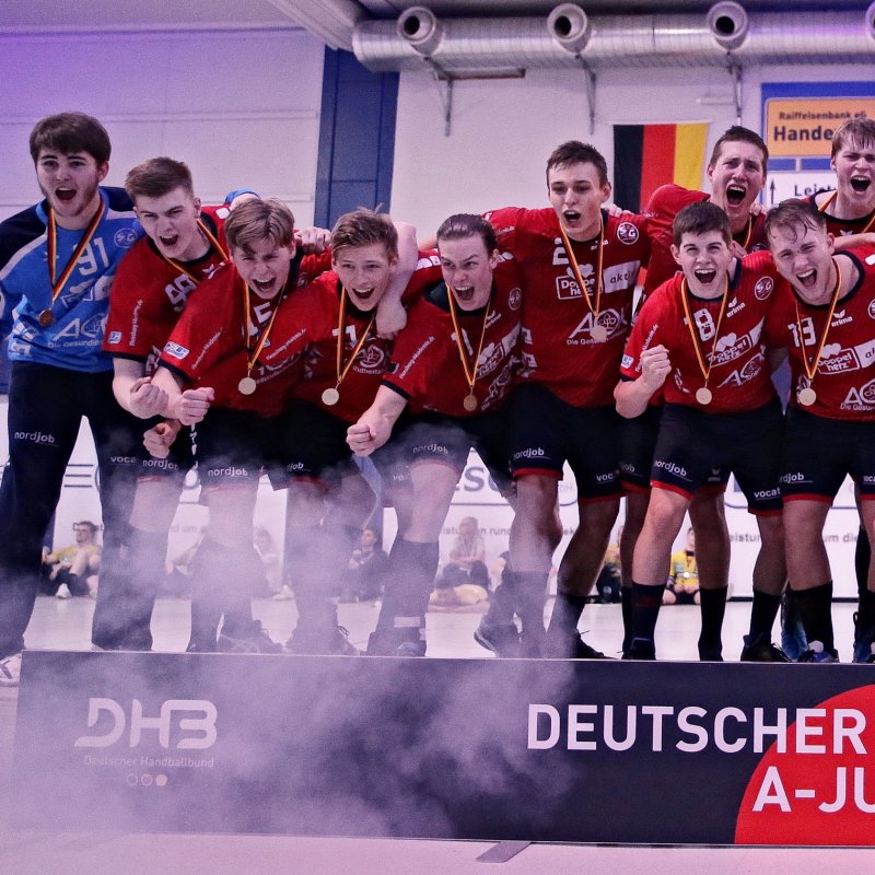 Junge Männer stehen hinter einer Bande und jubeln. Die Mannschaft hat eine Meisterschaft gewonnen.