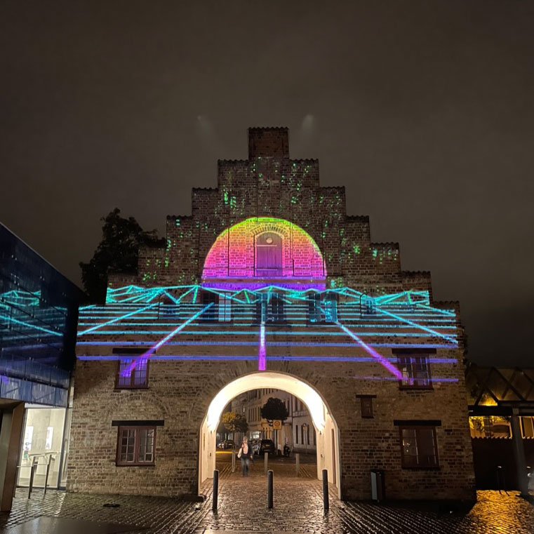 Angestrahltes Nordertor in Flensburg: Auf das historische Stadttor wird ein buntes, abstraktes Bild projiziert. 