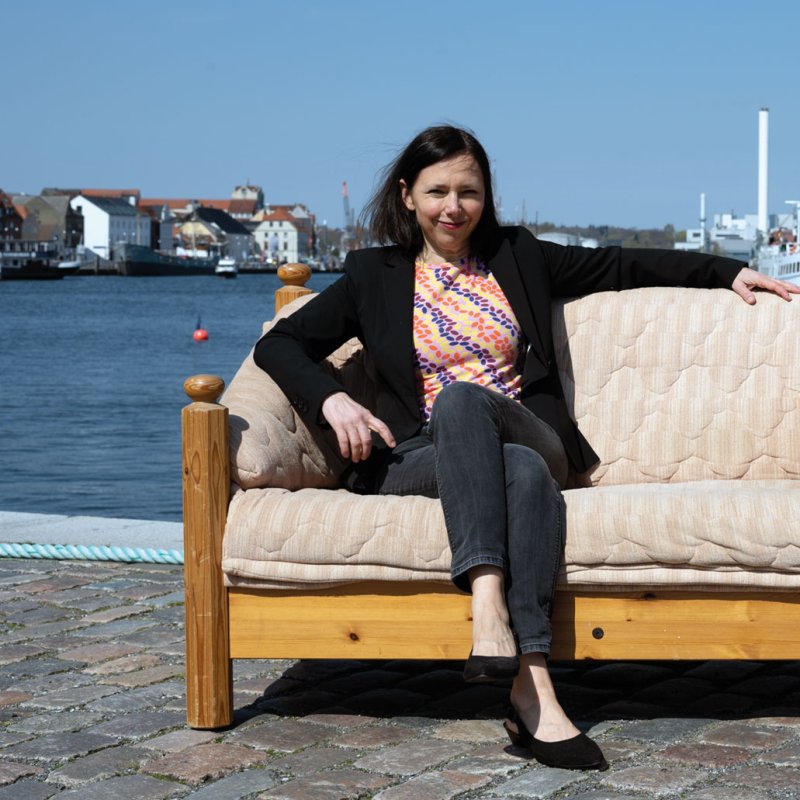 Angela Clemens sitzt auf einem Sofa, das am Flensburger Hafen steht.