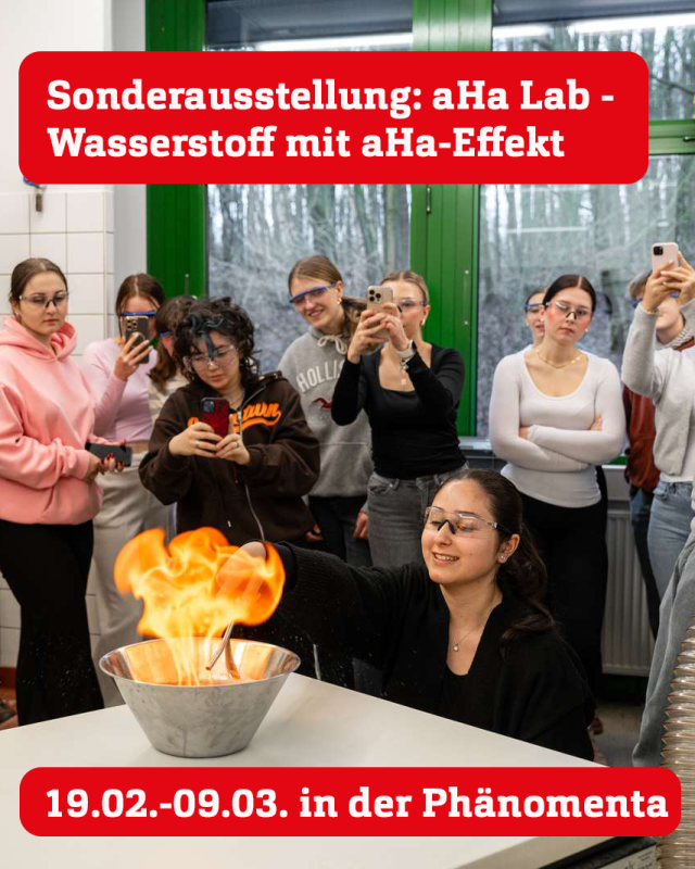 Eine Gruppe von Schülerinnen steht in einem Raum, sie tragen Schutzbrillen. Vor einem Tisch im Vordergrund hockt eine junge Frau mit Schutzbrille und lässt eine Flüssigkeit in einer Metallschüssel explodieren.