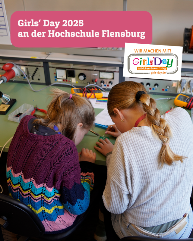 Zwei junge Mädchen sitzen an einem Tisch und basteln mit tief gebeugten Köpfen an einer elektrischen Schaltvorrichtung.