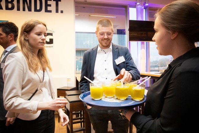 Drei junge Menschen um ein Tablett mit Getränken.