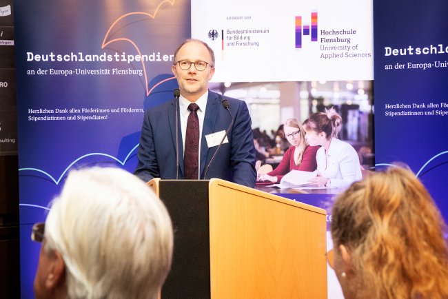 Mann im Anzug redet an einem Pult.