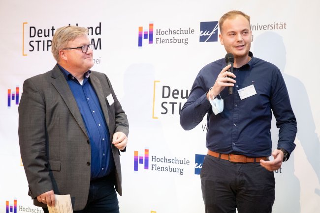 Zwei Männer mit Mikrofonen im Gespräch.