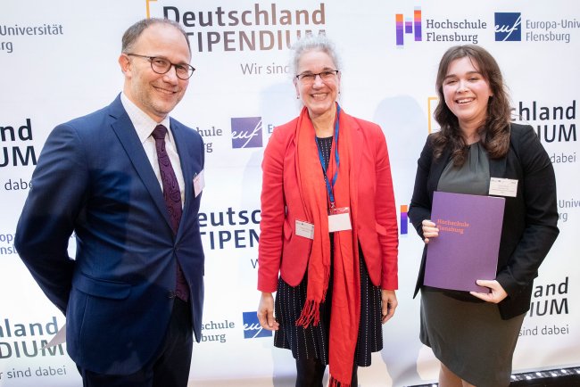 Drei Menschen, eine junge Frau mit Urkunde