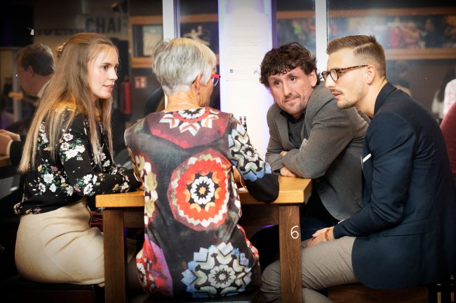 Vier Menschen an einem Tisch, sie sind ins Gespräch vertieft.