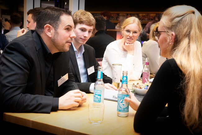 Eine Gruppe an einem Tisch, sie sind ins Gespräch vertieft.