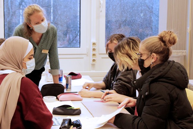 Mehrere Frauen um einen Tisch, sie arbeiten zusammen an etwas.