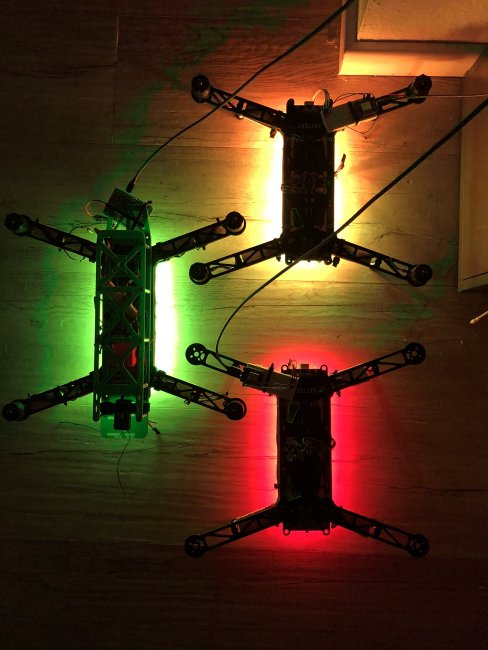 Drei Drohnen im Dunkeln, die gelb, grün und rot leuchten.