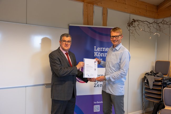 Der Vizepräsident übergibt ein Zertifikat an die Teilnehmer*innen