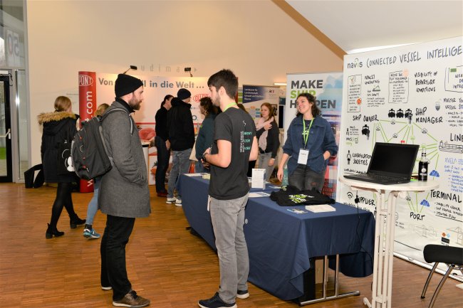 Personen unterhalten sich an einem Messestand