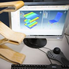 Arbeitsplatz im LTM-Labor: Auf einem Schreibtisch stehen ein Bildschirm, ein Controller und das Modell eines Stuhles. Das Modell ist auch in der Simulation auf dem Bildschirm zu sehen.