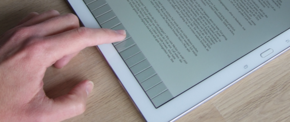 Hand und Tablet. Mit dem Zeigefinger berührt der Anwender den unteren Bereich des Tablet-Bildschirms, auf dem vertikale Linien zu erkennen sind.