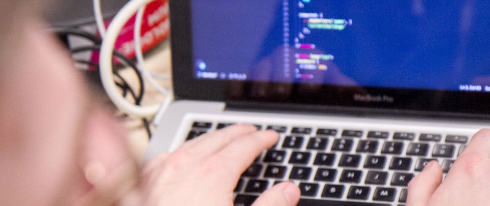 Blick auf einem Laptopmonitor, zu sehen sind einige verschwommende Zeilen Programmiercode