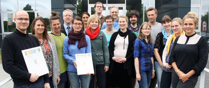 Gruppe aus Studierenden und Lehrenden, einge halten eine Urkunde in der Hand.