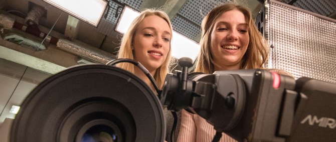 Zwei junge Frauen hinter einer Kamera.
