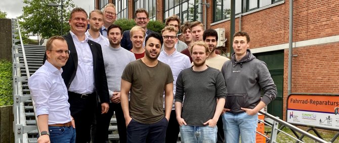 Gruppe von Studierenden und Lehrenden posieren auf einer TReppe. Sie lachen in die Kamera.