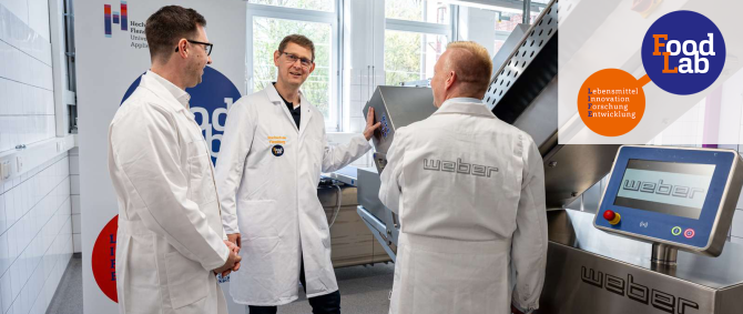 Drei Männer mittleren Alters in Laborkitteln stehen an einem mehr als mannshohen silbernen Laborgerät mit der Aufschrift "Weber".
